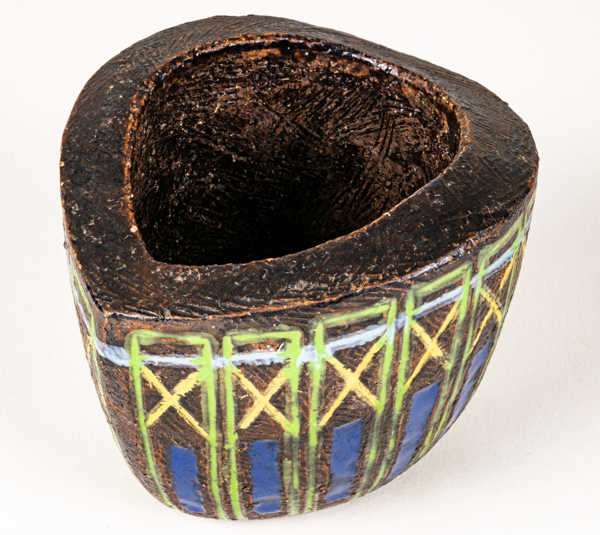 Bägare i svartbrun chamotte med blå, gula och gröna glasyrfyllda ristningar, formgiven av Berit Ternell 1953 hos Bo Fajans.