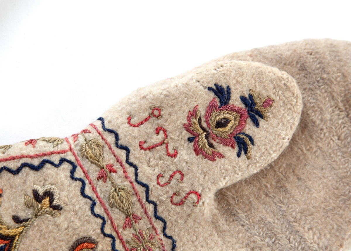 Hvite votter i nålebinding av ull med flerfaget broderi som dekor.