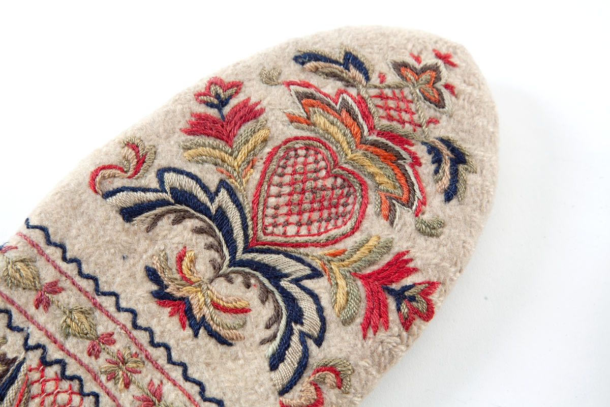 Hvite votter i nålebinding av ull med flerfaget broderi som dekor.