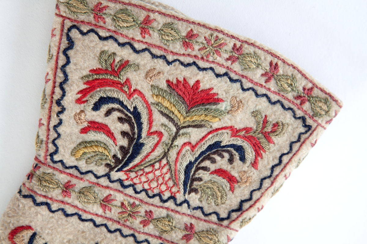 Hvite votter i nålebinding av ull med flerfaget broderi som dekor.