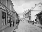 Parti av Storgatan i Linköping. Vy mot öster vid skärningen av Apotekaregatan. Närmast till vänster ses Axel Karlssons Manufakturhandel och nedanför skymtar apotek Vasen. Byggnaden är flyttad till friluftsmuseet Gamla Linköping och har fått ny funktion som värdshus. Till höger skymtar Granbomska gården följt av den Bielkeska, där Eduard Andersson vid tiden drev sin garn- och vävnadshandel. Byggnaden uppfördes av familjen Bielke i början av 1800-talet för att fungera som familjens så kallade vinterviste.