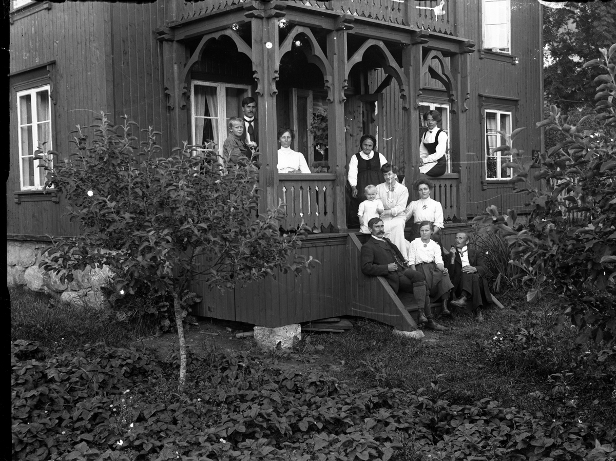 Fotosamling etter Kjetil Skomdal (1881-1971). Fotografen virket i perioden 1910 til 1960 og hadde eget mørkerom hvor han også tok imot film fra andre fotografer. I perioden var han også postbud i Fyresdal. Gruppeportrett av familie på trapp.