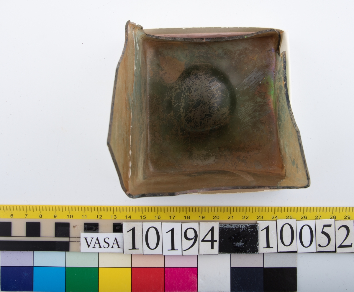 Botten samt fyra skärvor från fyrsidig flaska med stucken botten. På bottnens undersida finns ett puntelmärke. Glaset är grönfärgat och har en iriserande beläggning.

No damage. All pieces are a light green color and are from a case bottle.
10194a: has worn spot
10194c: Consists of two artifact numbers that have been glued together. Artifact has moderate scaling.