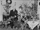 Man i hemmiljö omgiven av blommor, Uppland 1950