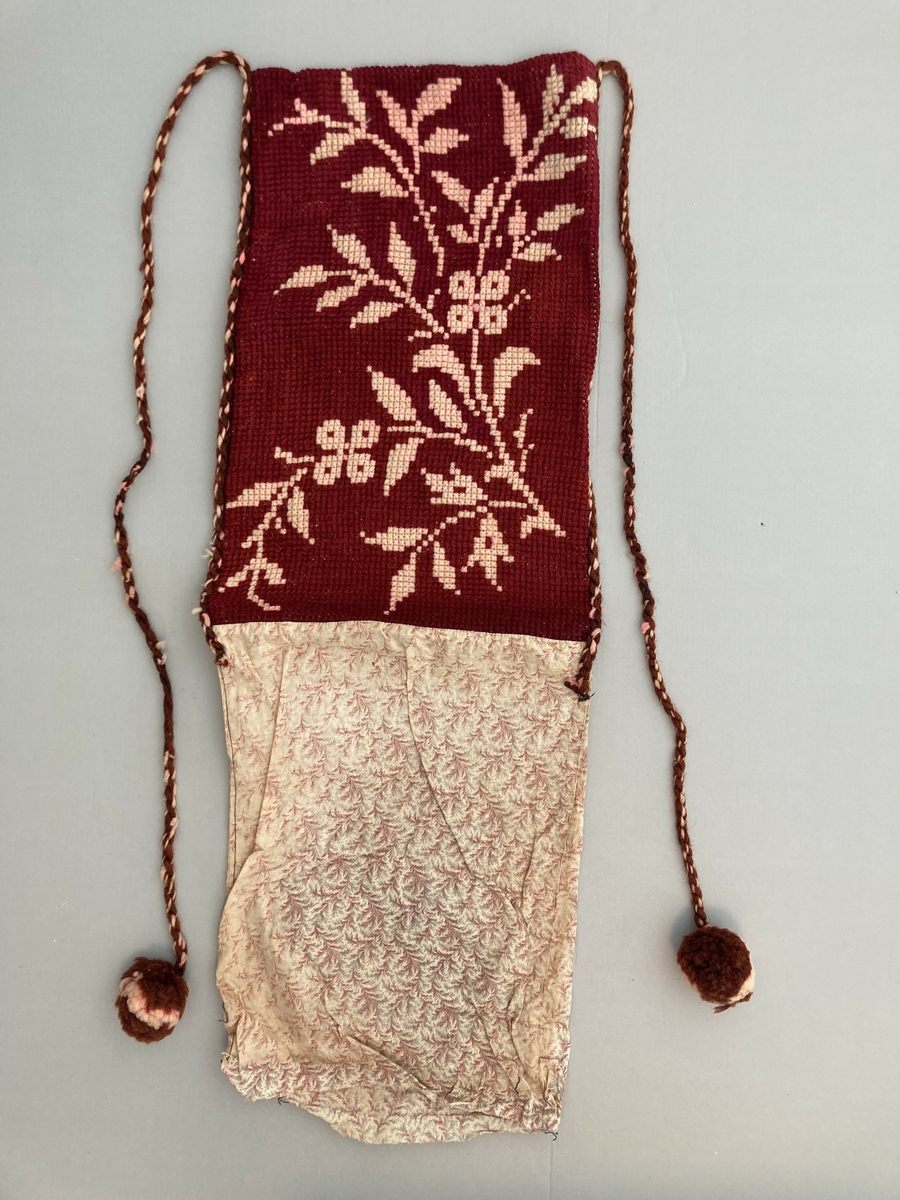 Brev-veske til oppbevaring av post? Sauma i mønstret stoff. På halve stoff-lengda er det sauma på ein brodera del. Dobbel korssting. 2 tvinna gån (garn) med duskar i endane.