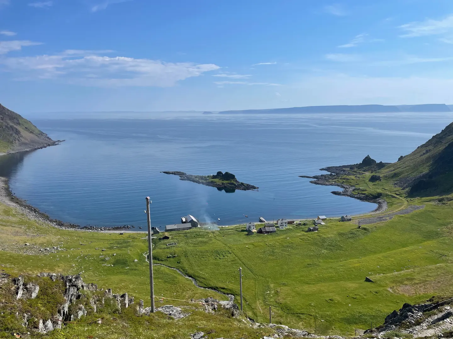 En bukt i sollys, sommerdag, hav og gress.