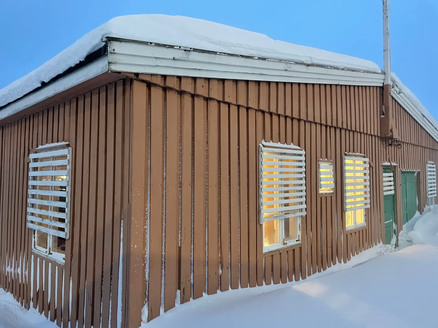 Brakke sett utenfra om vinteren i snø og kveldssol.