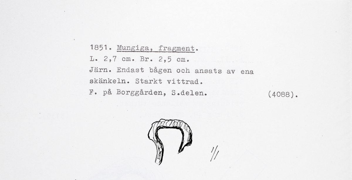 Del av en mungiga. Endast bågen och ansats av ena skänkeln bevarad. Starkt vittrad.