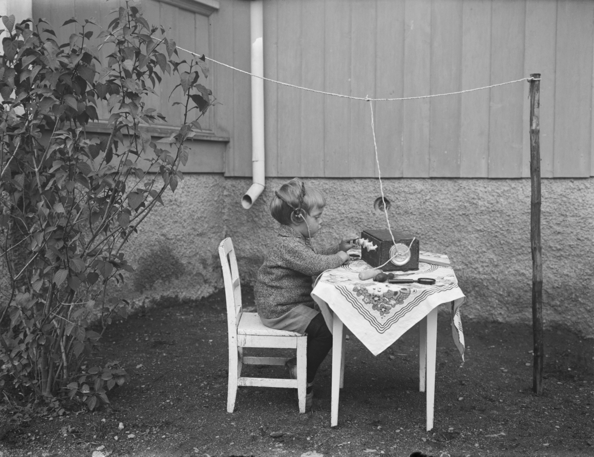 Liten gutt sittende ved et bord. Radioamatør. Gunnar Berge på "radio".