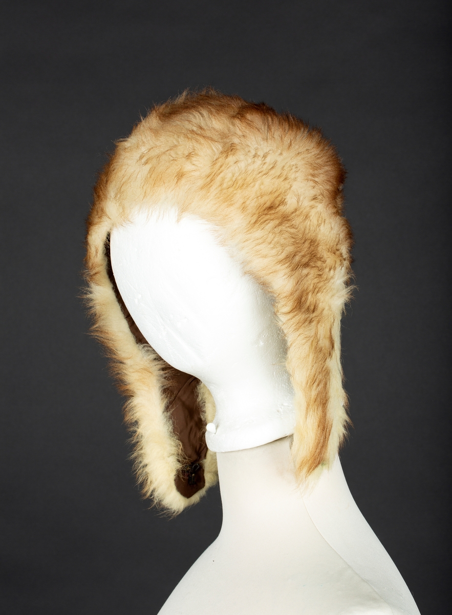 Hjelmelue i imitert pels. Knapping av sideklaffer under haken