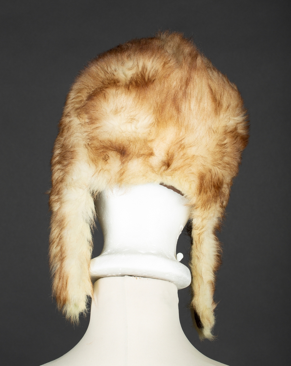 Hjelmelue i imitert pels. Knapping av sideklaffer under haken