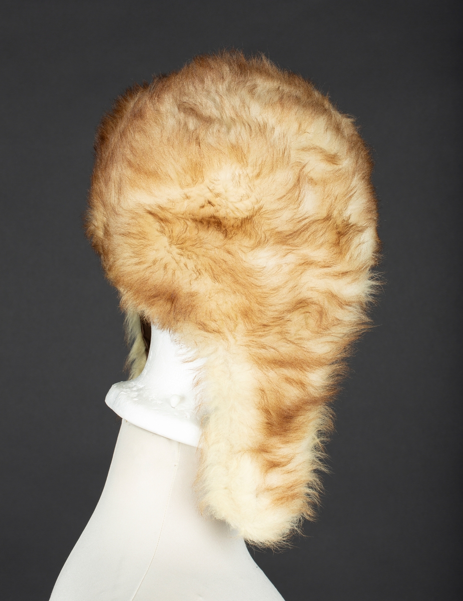 Hjelmelue i imitert pels. Knapping av sideklaffer under haken