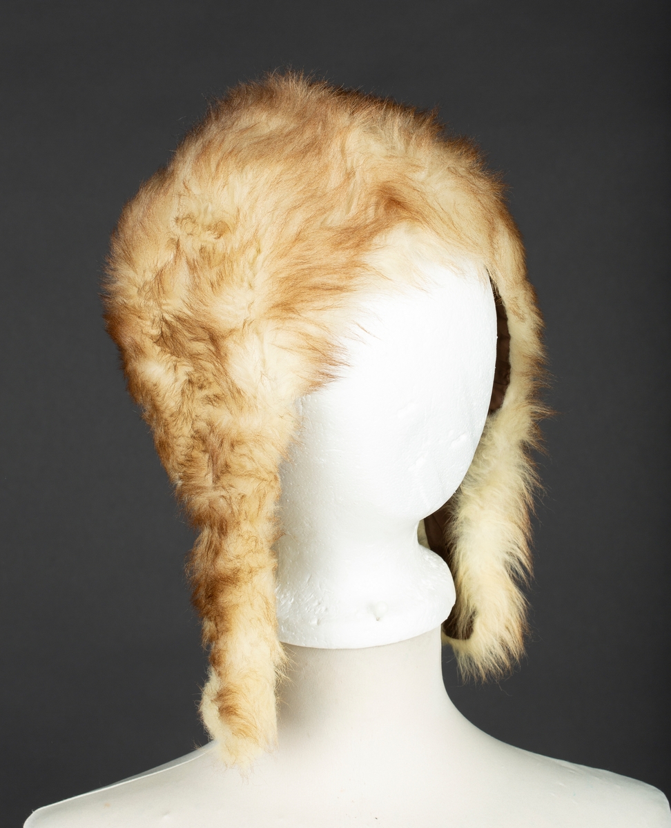 Hjelmelue i imitert pels. Knapping av sideklaffer under haken