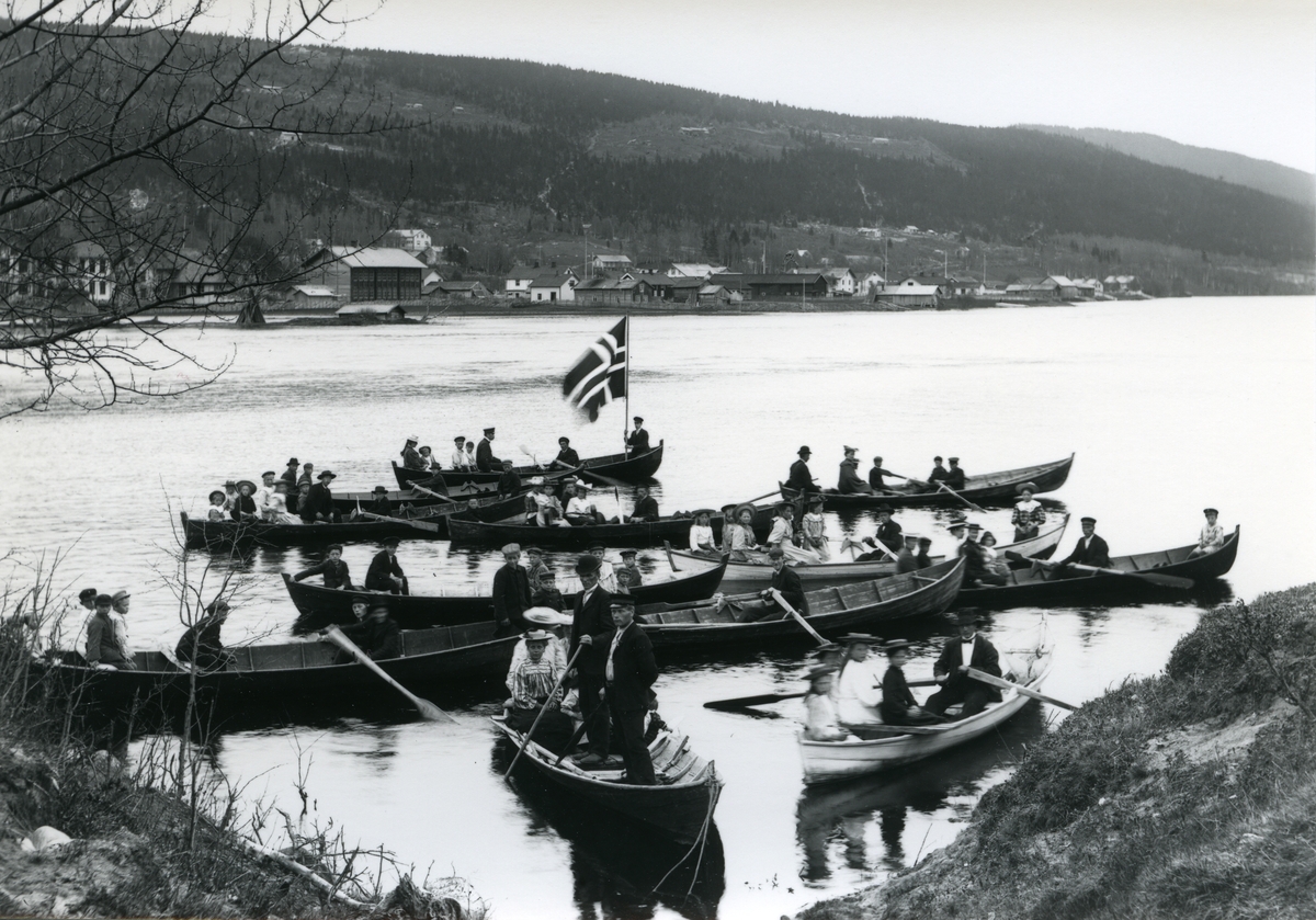 12  båter på Trysilelva ved vestlandet i Innbygda, omtrent ved den gamle brua (Kirkebrua åpnet 1912). På østsida fra Tingvang til S. Bæk.
