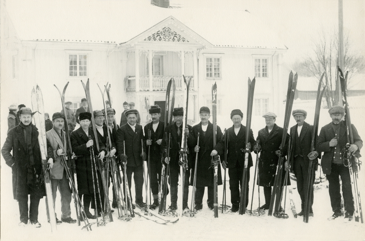 13 skiløpere fotografert foran Fladhagen. Fra venstre Svend Næs (1849-1937), Olaf Lokholt, Olaf Flenmoren (1884-1957), Helenus Bakken (1884-1957), Per Bakken (1882-1958), Lars Neby (1884-1975), Henning Mobæk (1877-1966), Per Andreassen (1879-1936), Daniel Grønoset (1877-1965), Elling Rønes (1822-1965), Theodor Olsen (1869-1950), Halvor Sandkveen (1857-1936), Gunder Løvåsen (1846-1929).