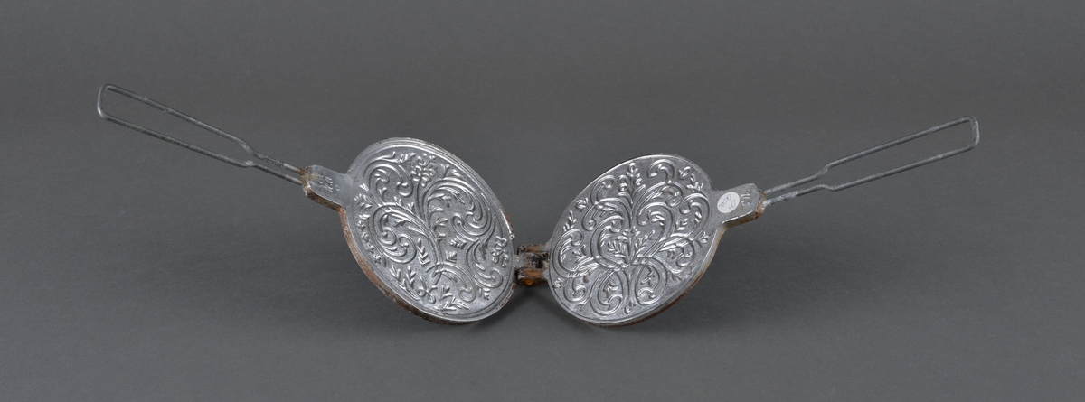 Lite krumkakejern for steining av krumkaker. 
Legges på plate e.l. 
Dekor på innsiden av stekeplatene.