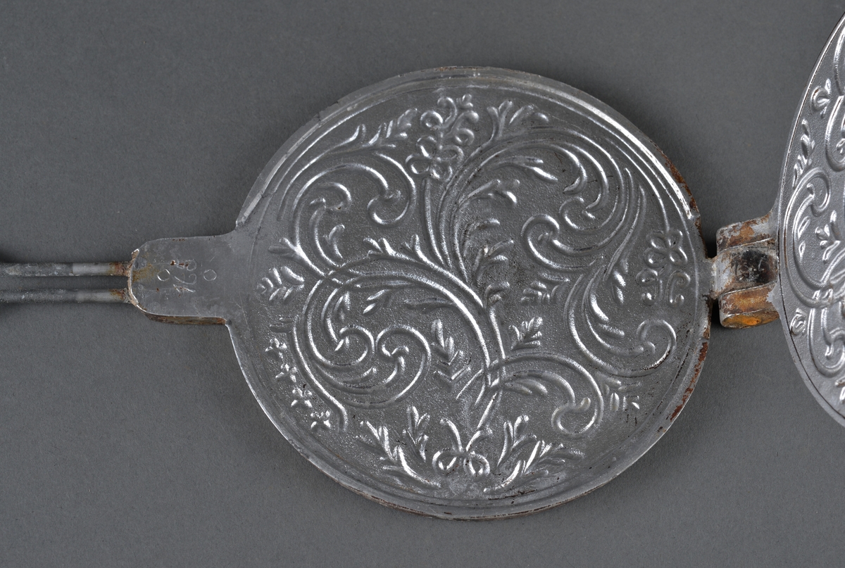 Lite krumkakejern for steining av krumkaker. 
Legges på plate e.l. 
Dekor på innsiden av stekeplatene.