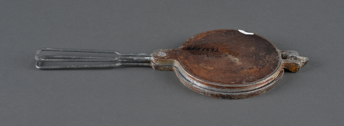 Lite krumkakejern for steining av krumkaker. 
Legges på plate e.l. 
Dekor på innsiden av stekeplatene.