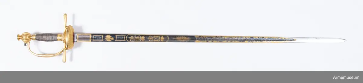 Grupp D II.
Fästet är av kommendertyp  med rak eneggad klinga, som är rikt dekorerad på bägge sidor med bl a Carl XIV Johans och kronprins Oscars namnchiffer.