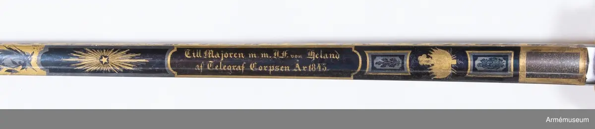 Grupp D II.
Fästet är av kommendertyp  med rak eneggad klinga, som är rikt dekorerad på bägge sidor med bl a Carl XIV Johans och kronprins Oscars namnchiffer.