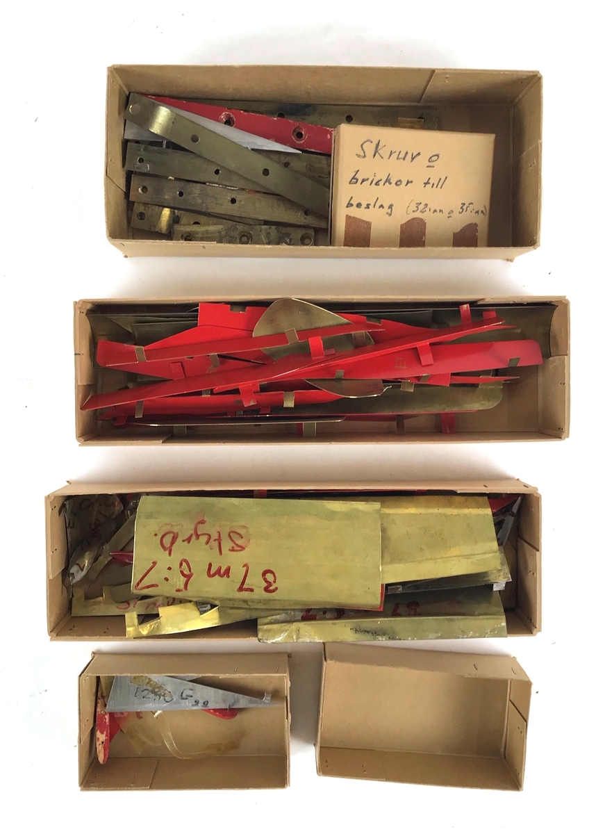 Låda med delar till vindtunnelmodell av Saab 35 Draken. Främst fenor och vingdelar.