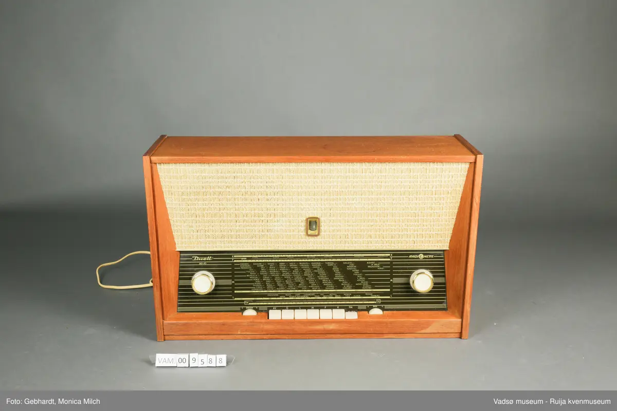 Stor treradio fra Radionette. Radioen har en glasskjerm på framsiden. På bakveggen, som kan tas av, er detaljene om radioen og bruken av den skrevet ned.
