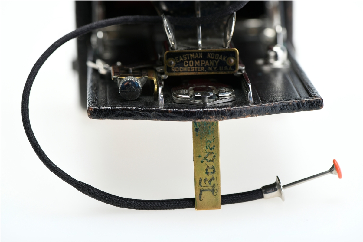Et belgkamera for 116-film fra Kodak. No. 1A Folding pocket ble laget i flere versjoner mellom 1899 og 1915 og var det første kameraet fra Kodak til å bruke 116-film. Av de fire versjonene (Model A, B, C, D) var denne Model D den første til å ha en objektivplate i metall, mens de tidligere versjonene hadde en objektivplate i tre. 

Kameraet tar bilder på 6,5x11 cm. Det har 3 lukkertider i tillegg til åpen lukker (B). I tillegg til lukkeren på objektivet har kameraet også en snorutløser. På skinnen som belgen er festet i er det et lite hjul for å stoppe belgen i ulike posisjoner merket med fokusavstand. Det er en søker foran på objektivplaten som kan roteres for å ta landskapsbilder, og søkeren har et deksel som kan vippes opp. Baksiden kan åpnes for å sette inn film, og det har et rødt vindu for å se om det er film i. Luken til belgen åpnes med en knapp på siden av kameraet, på luken er det en fot som kan brettes ut. Håndtak i skinn på toppen. Kameraet kommer i en veske av skinn. Med kameraet følger også en mekanisk opptrekkbar selvutløser som kan festes på enden av snorutløseren.