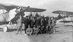 Gruppfoto av flygvapenpersonal framför flygplan S 6 Fokker C.V med övningsmärkning, omkring 1929-1931. Suddig bild.