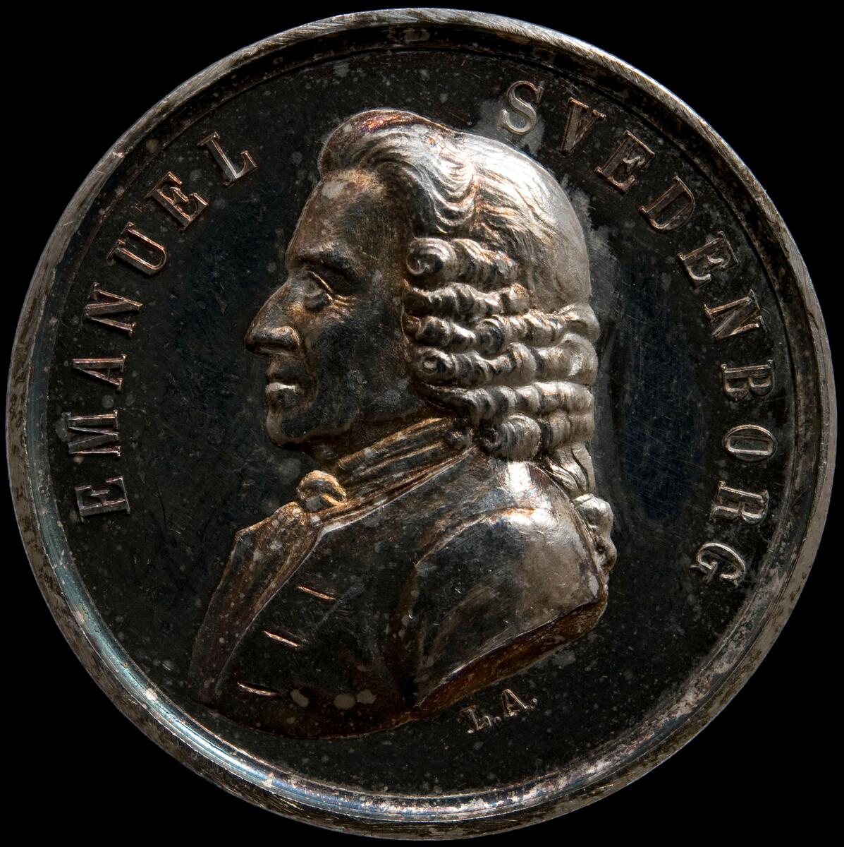 Medalj Emanuel Swedenborg (1688-1772). Assessor i Bergskollegium. Åtsidan: Namn och bröstbild. Frånsidan: QUAERENTI DEFUIT ORBIS. En man i antik dräkt, med en fackla i handen, gående vid en bergsvägg, redo att stiga ned i de dödas rike. Men någon ingång finns inte i berget. Gravör: Lea Ahlborn. 1858 av Svenska akademien. 