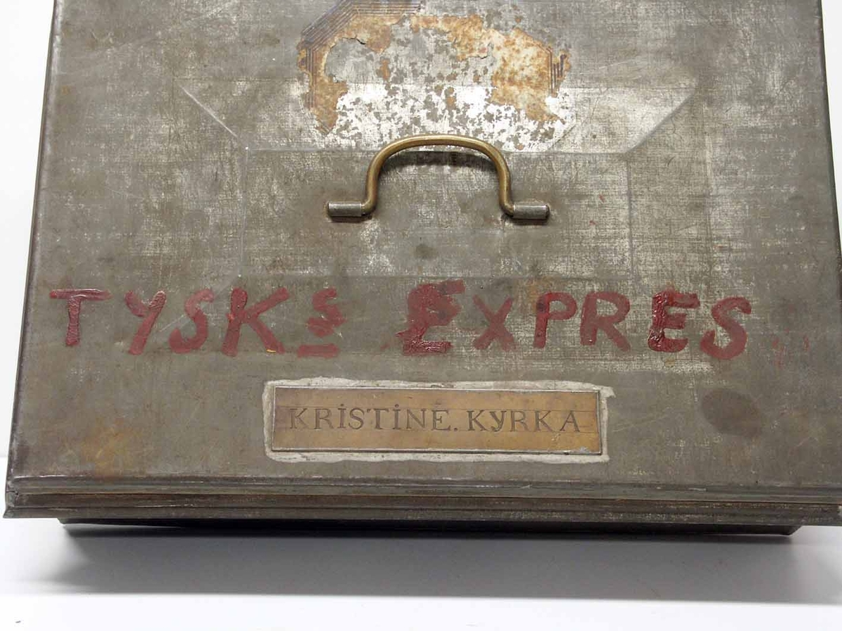 Kassaskrin av plåt med kopparskylt utanpå: "Kristine kyrka", ovanför skylten har skrivits i röd färg: "Tysks express". Innehåller sedel och myntfack varav några inte tycks vara ursprungliga.