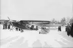 Flygplan ASJA Viking II, med civilregistrering SE-FYR tillhörande Svensk Filmindustri och Stockholmstidningen samt flygplan Flygande Loppan står på ett fält, vintertid, cirka 1935-1941. Folksamling kring flygplanen.