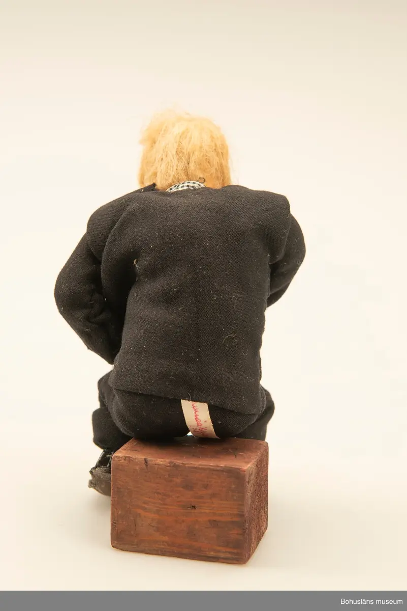 Gubbe med psalmbok sittande på en träkub