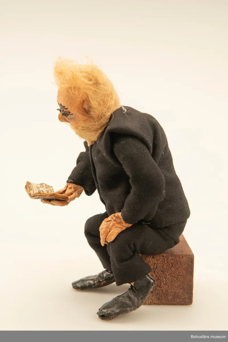 Gubbe med psalmbok sittande på en träkub