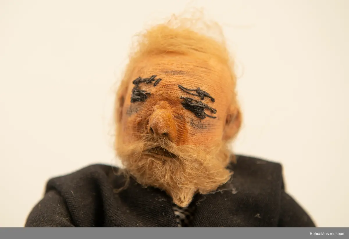 Gubbe med psalmbok sittande på en träkub