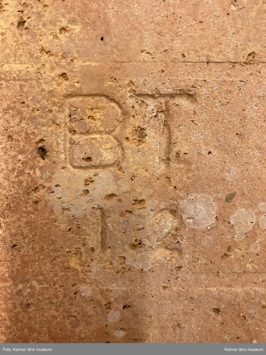 KLM 46605. Tegelsten, murtegel. Av tegel. Rektangulär form. Strängpressat. Stämpel: BT och 1.2.