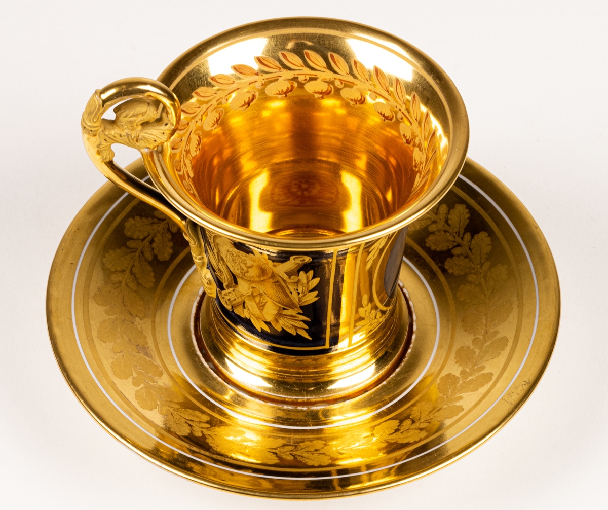 Karl XIII:S kopp.
Kopp med fat från Daite Freies i Paris, omkring 1800.
Koppens höjd 9.5 cm. Fatets diameter 16,5 cm.
Koppen bär på ena sidan Karl XIII:s bild och är på motstående sida dekorerad med ett par antika hjälmar.
Dekor i empirestil i guld och blått.
En grepe med örnhuvud och palmettdekor. Fatet är dekorerat med en eklövskrans.