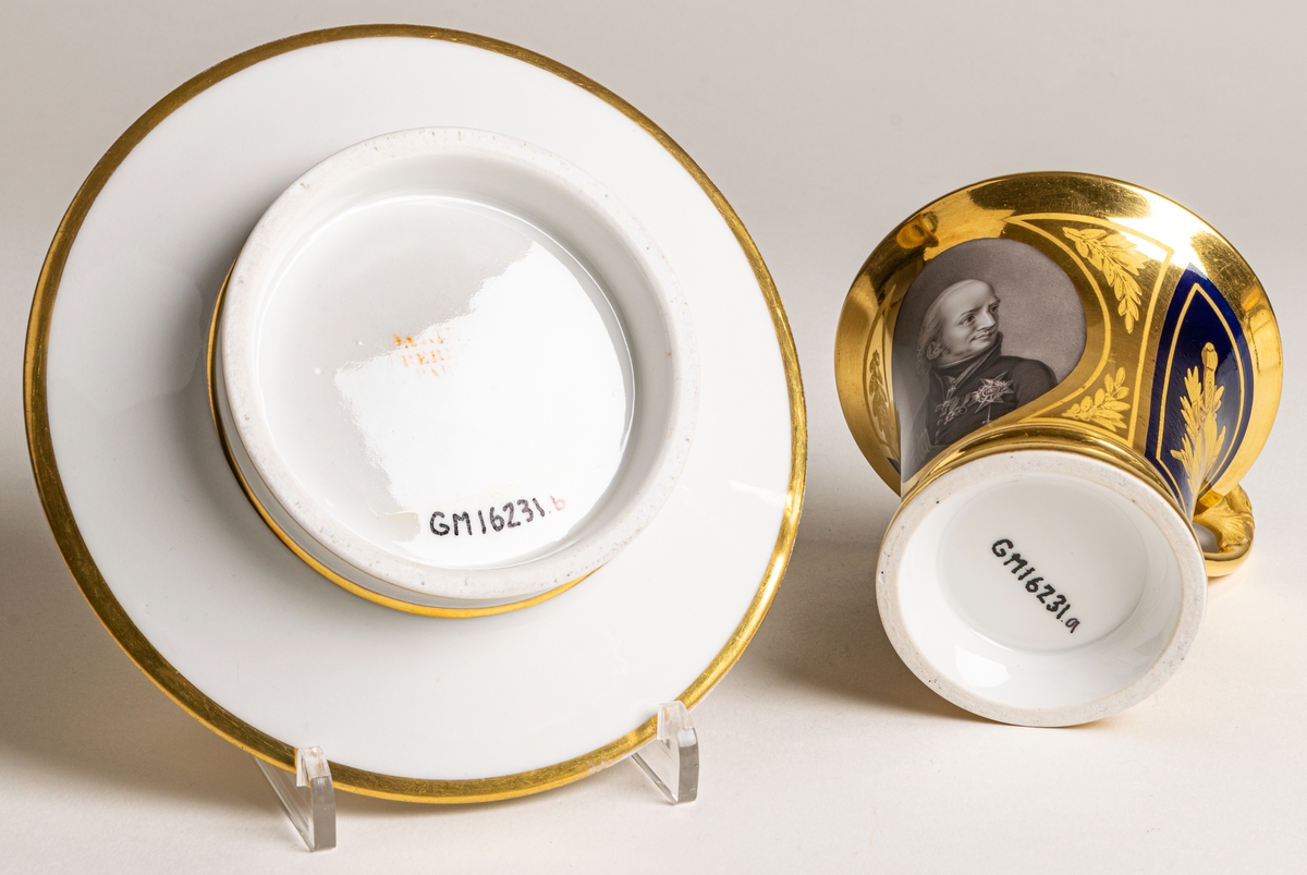 Karl XIII:S kopp.
Kopp med fat från Daite Freies i Paris, omkring 1800.
Koppens höjd 9.5 cm. Fatets diameter 16,5 cm.
Koppen bär på ena sidan Karl XIII:s bild och är på motstående sida dekorerad med ett par antika hjälmar.
Dekor i empirestil i guld och blått.
En grepe med örnhuvud och palmettdekor. Fatet är dekorerat med en eklövskrans.