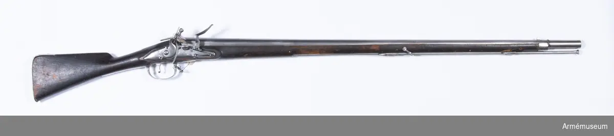 Grupp E II.
Gevär med flintlås.
Kal. 20,3 mm. Sannolikt reparationsmodell från 1700-talets slut. Sammansatt av delar till äldre gevär. Laddstock av järn. Varhaken saknas. Pipan tillverkad i Norrtälje. Märkt "2" över "86", en punkt och "6."