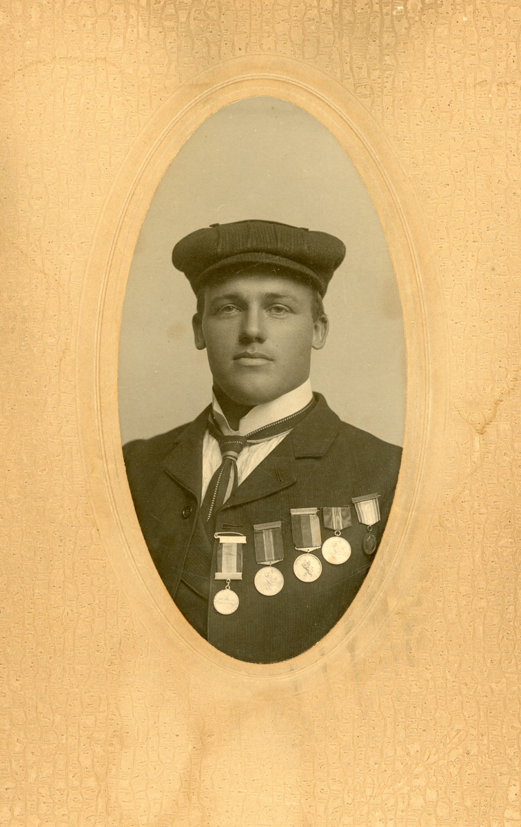 Ovalt brystbilde av Knut G. Helland i Amerika i 1906. Han har fem skimedaljer på brystet.