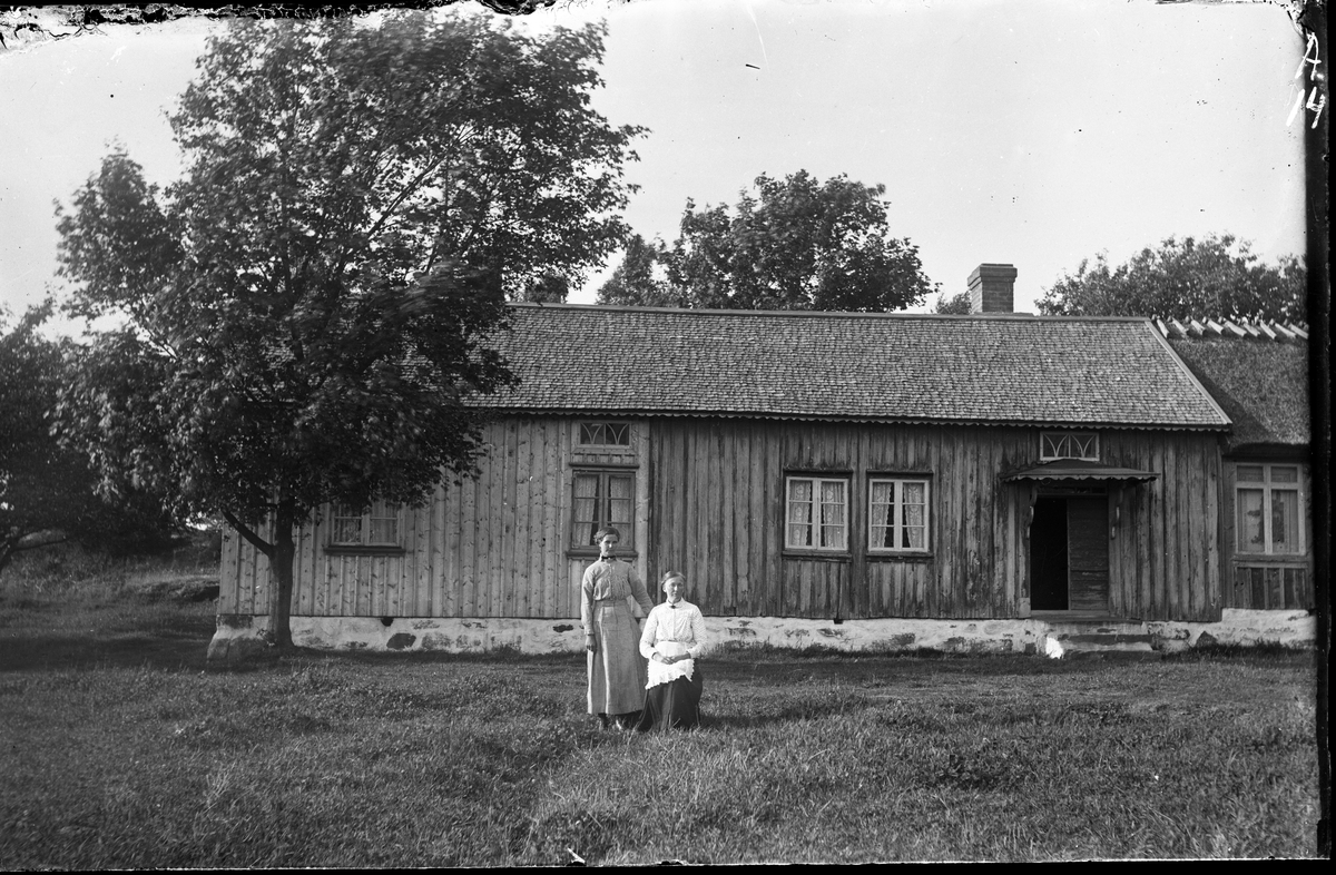 Detta var det s k organistbostället i Hästhagen som låg i den västra delen av Sällstorp. Det kallades även Engbergs, efter Gunnar Engberg som var lärare och organist i socknen före Engström. Framför huset sitter Anna Matilda Magnidotter, "Engbergs-Tilda", från grannstället Klingeberg och dotter till Magnus Olsson. Hon och maken snickaren Nils August Berntsson bodde här. De fick inga barn. Den yngre kvinnan som står bredvid henne är dotter till Tildas syster Johanna Britta och hette enligt uppgift troligen Anna Elemina.

Huset ser ut att ha ny panel på den vänstra delen och kanske är även sticktaket nylagt. Både portens skärmtak på rundade konsoler och takfoten är försedda med smal, figursågad dekor. Huset är sammanbyggt med en annan huskropp åt höger som har stråtak. Det stora fönstret ser ut att ha en rullgardin nere, med motiv föreställande en kyrka, borg eller liknande på ett berg.