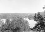 Motiv från Hannäs med panorama över Nystadviken i sjön Vindommen. Till vänster på kullen skymtar församlingens gamla kyrka som vid tiden nyligen lagts i ruin och ersatts med den nya kyrkan som anas i bakgrundens dis.