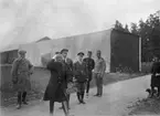 Militärer och civila i rörelse framför en tillfällig hangar för flygplan av AEG-typ på Flygkompaniet på Malmen, omkring 1918-1920.