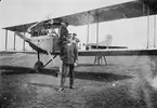 Flygplan NAB 9, Albatros nr 854 står uppställd på bock på ett flygfält. En flygspanare står framför flygplanet och två flygmekaniker sitter i flygplanet. Omkring 1919-1925.