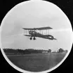 Civilregistrerat flygplan Avro 504 startar från flygfältet på Malmen, omkring 1919-1920. I bakgrunden syns bygdevägen mot Malmslätt och Röda och Gula förråden.