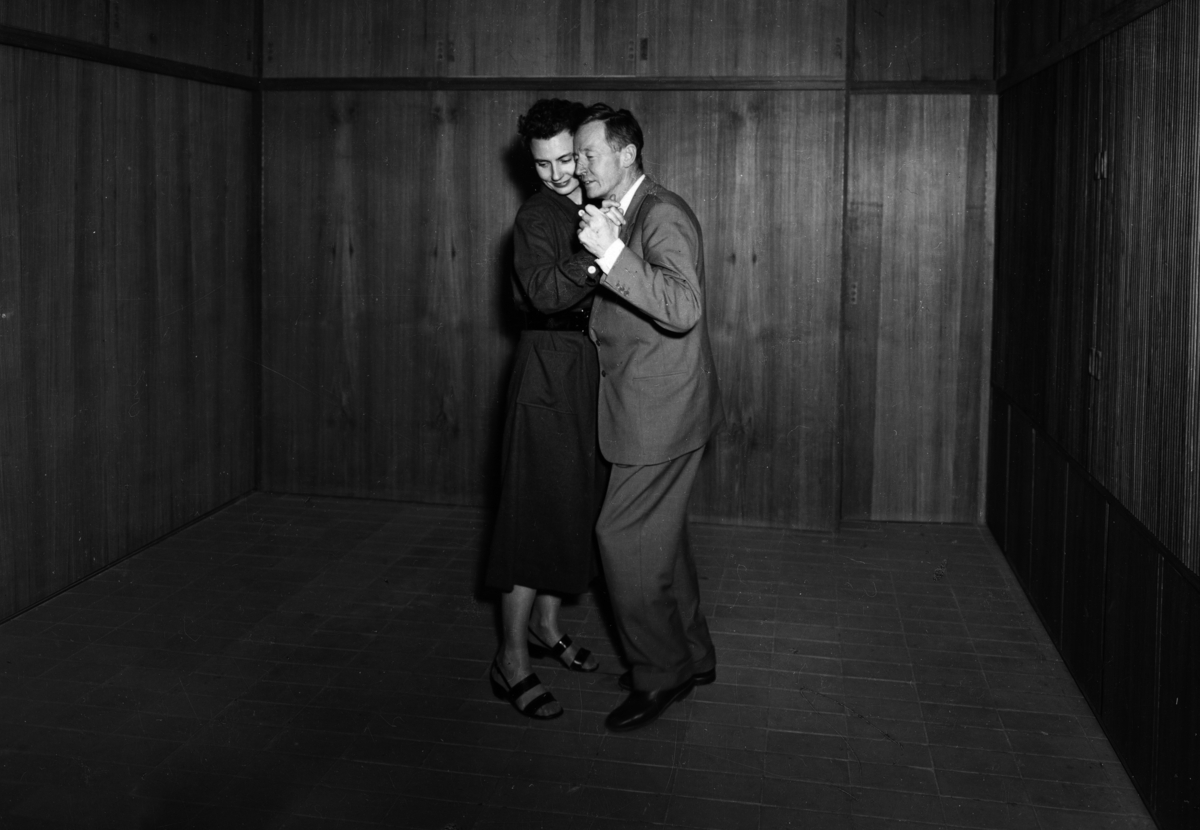 Foto av et dansende par i Planetveien 12, Arne Korsmo og  Grete Prytz Kittelsens enebolig på Vettakollen i Oslo. Bygningen er tegnet av Korsmo og Christian Norberg-Schulz og ble bygget i 1954. Huset regnes som et av de viktigste verkene i norsk modernistisk, funksjonalistisk arkitektur, og er tegnet etter prinsippet om at alle form skal fylle en funksjon.