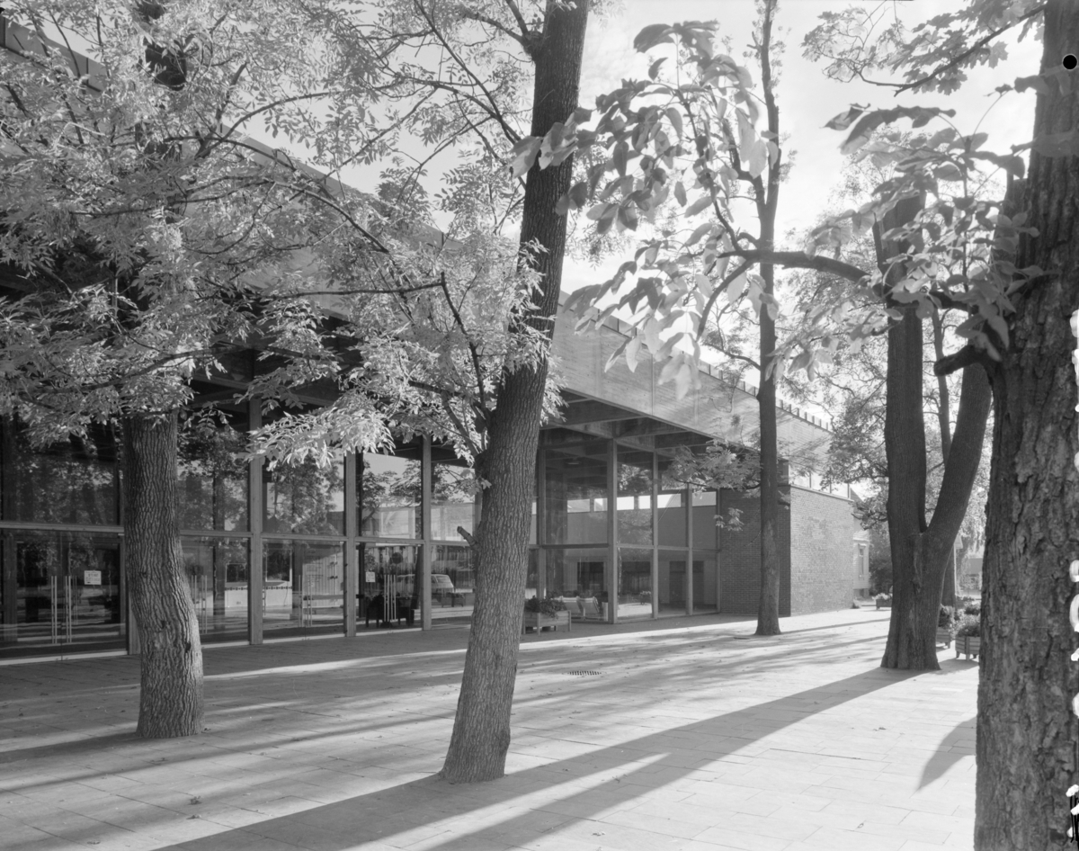 Arkitekturfoto av Ibsenhuset i Skien, fra arkitektens hjemmeside:   "Kulturhus for teater, kino, konserter, kunstutstillinger, bibliotek og publikumsfasiliteter.  Bruttoareal: 8 500 m2 Oppdragsgiver: Skien kommune Ferdigstilt: 1973  Prosjektet bygger på 1.premieutkastet i åpen arkitektkonkurranse 1967. Plasseringen på tomten lar bygningen danne fondvegg i parken, samtidig som mest mulig av parken med dens store trær tas vare på, - i åpen sammenheng med bygningens vestibyle. Planer og konstruksjoner åpner både for store sammen-hengende rom og for fleksible sambruksmuligheter med krav til visuell oppdeling og lydskjerming."