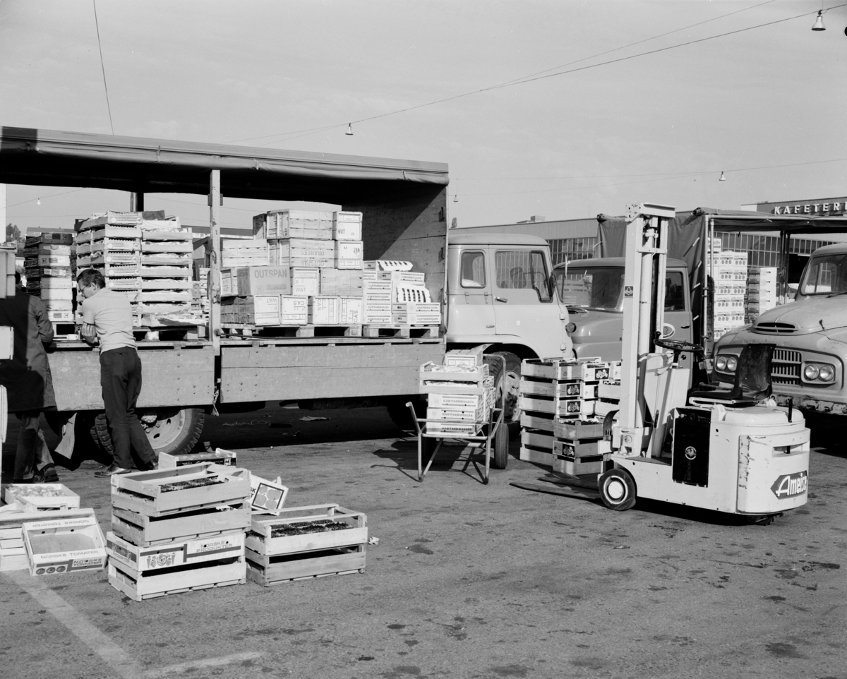 Gaffeltruck laster trekasser inn i en lastebil. To menn snakker sammen.