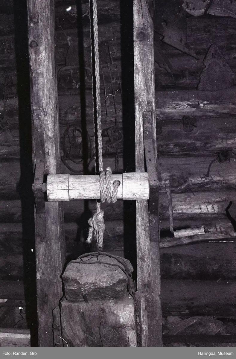 Plogpresse.
2 loddrette trestokkar (frå golv til tak), 270 cm. høge med 35 cm. mellomrom. Nedst mellom trestokkane er ein telgt trekubbe, på oversida av denne er jarnskoning i plogskjerform. Over denne er ein trekubbe med tilsvarande jarnskoning på undersida, på oversida av denne trekubben er ein stein festa med jarn, hempe i jarnet her. I hempa er eit tog som går over ei talje øvst på heile pressa, vidare ned til ein rund stokk med sveiv (for å lyfte kubben med steinen).
H.: 270 cm.
Ytre breidde: 54 cm.
Ytre breidde med sveiv: 72 cm.
