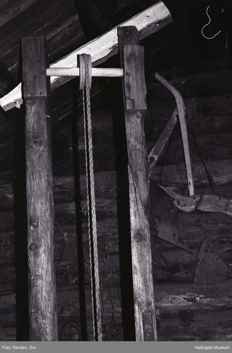 Plogpresse.
2 loddrette trestokkar (frå golv til tak), 270 cm. høge med 35 cm. mellomrom. Nedst mellom trestokkane er ein telgt trekubbe, på oversida av denne er jarnskoning i plogskjerform. Over denne er ein trekubbe med tilsvarande jarnskoning på undersida, på oversida av denne trekubben er ein stein festa med jarn, hempe i jarnet her. I hempa er eit tog som går over ei talje øvst på heile pressa, vidare ned til ein rund stokk med sveiv (for å lyfte kubben med steinen).
H.: 270 cm.
Ytre breidde: 54 cm.
Ytre breidde med sveiv: 72 cm.
