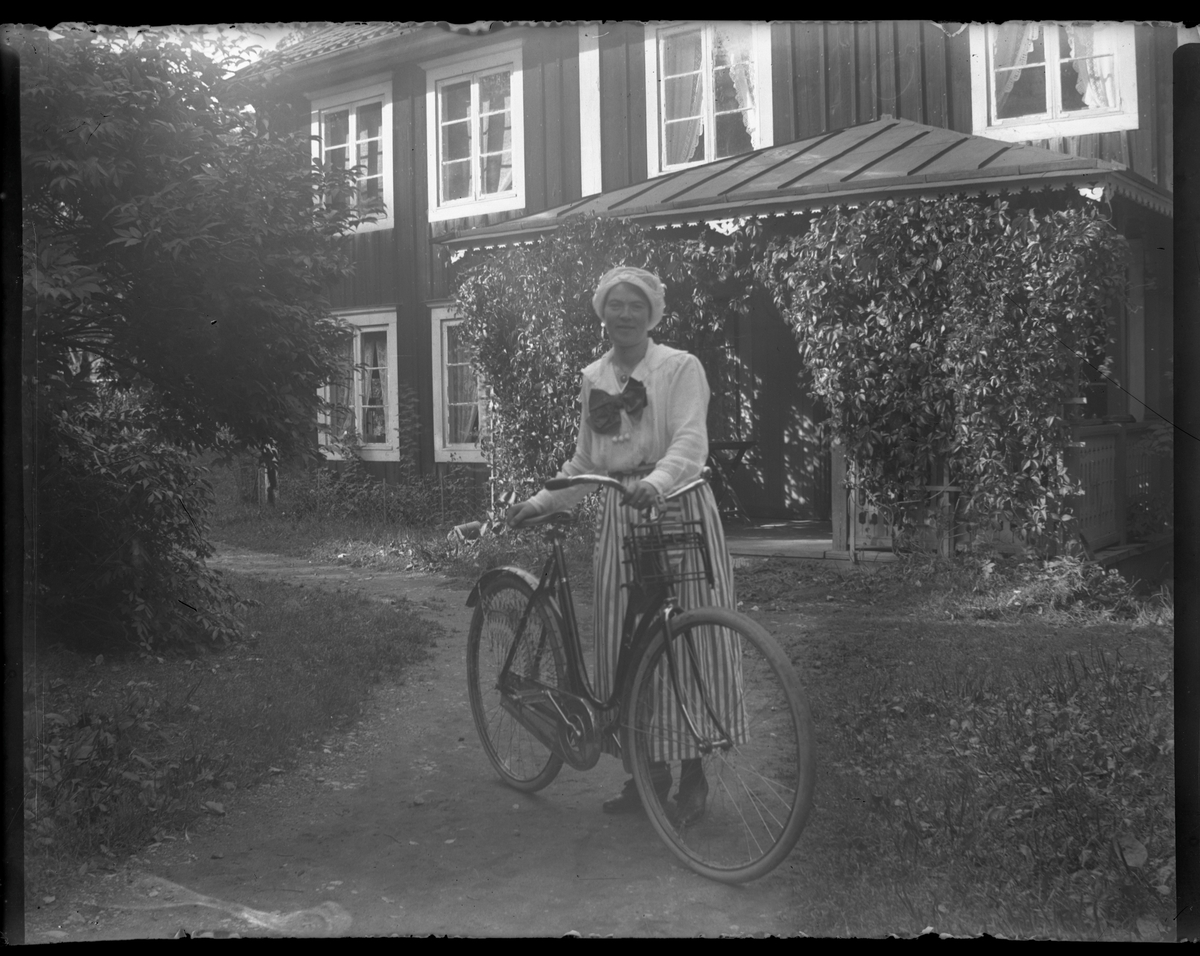 Porträtt, kvinna med cykel framför veranda.